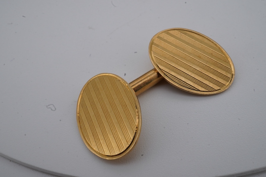 A pair of gold cuff-links, each end of oval outline with striped engraving, to a bar connector, each end 1.8cm, each stamped 18ct, combined gross weight approximately 9.5 grams, maker's marks EH, case stamped Jay's, Cond
